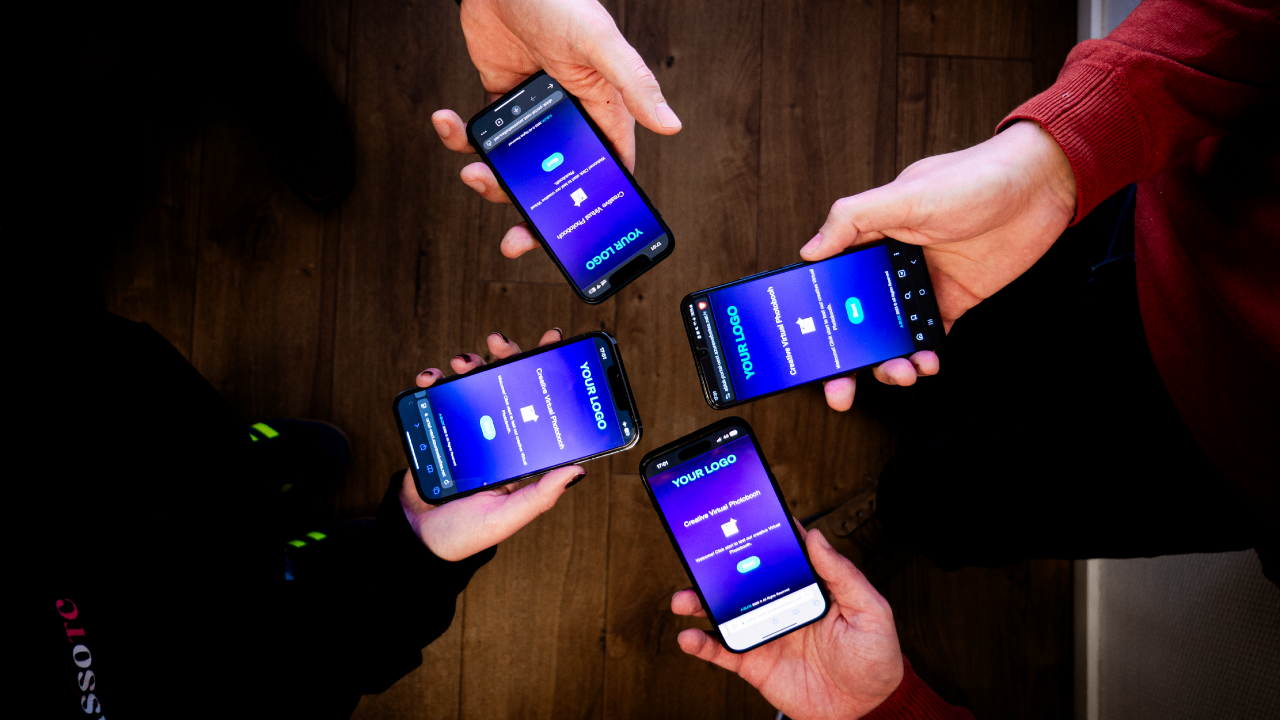 Vier Hände halten Handys, auf denen die interaktive Virtuelle Fotobox-App zur Teilnehmeraktivierung sichtbar ist