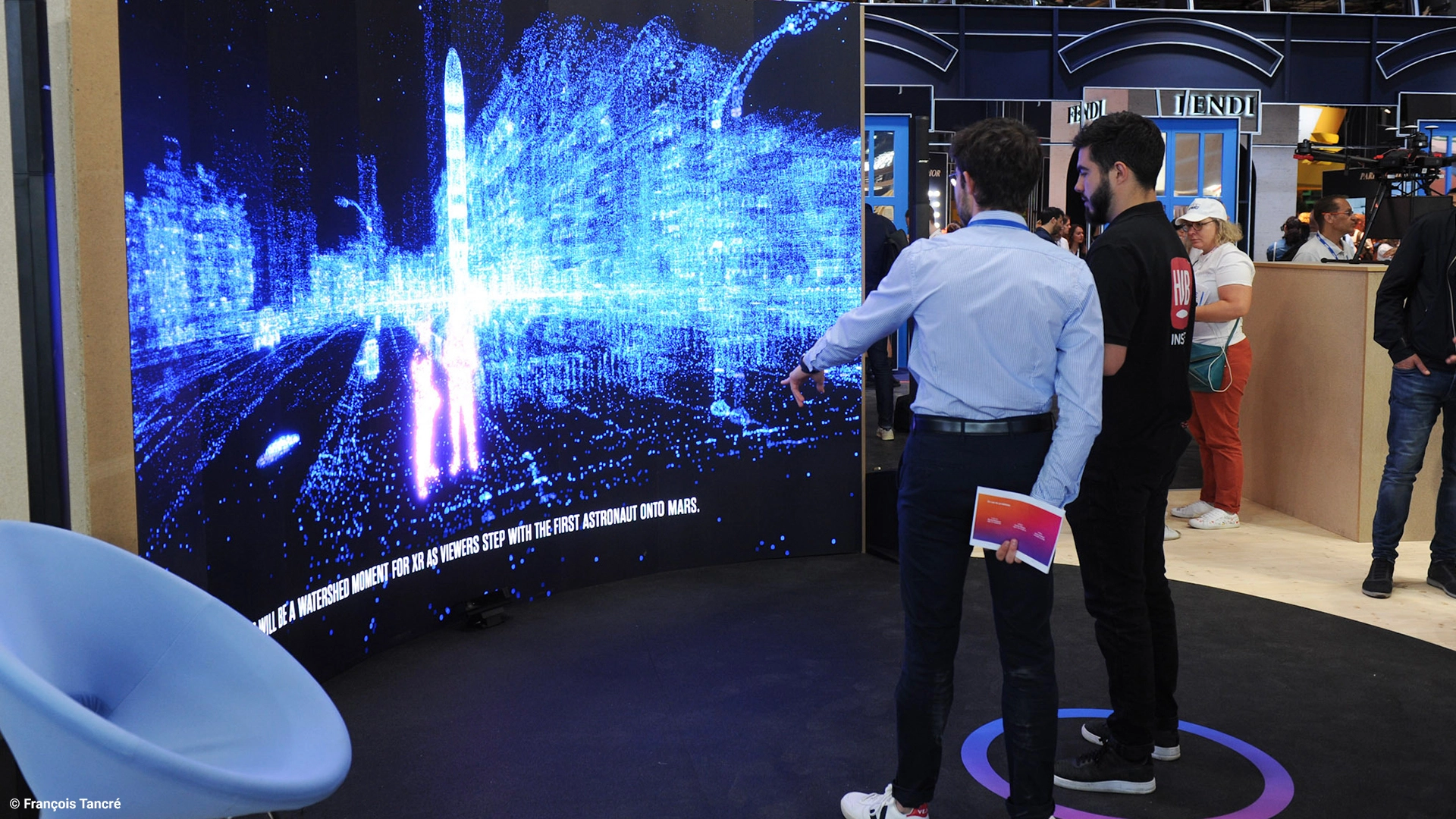A KPMG consultant talks to a visitor in front of the Beyond Metaverse interactive installation