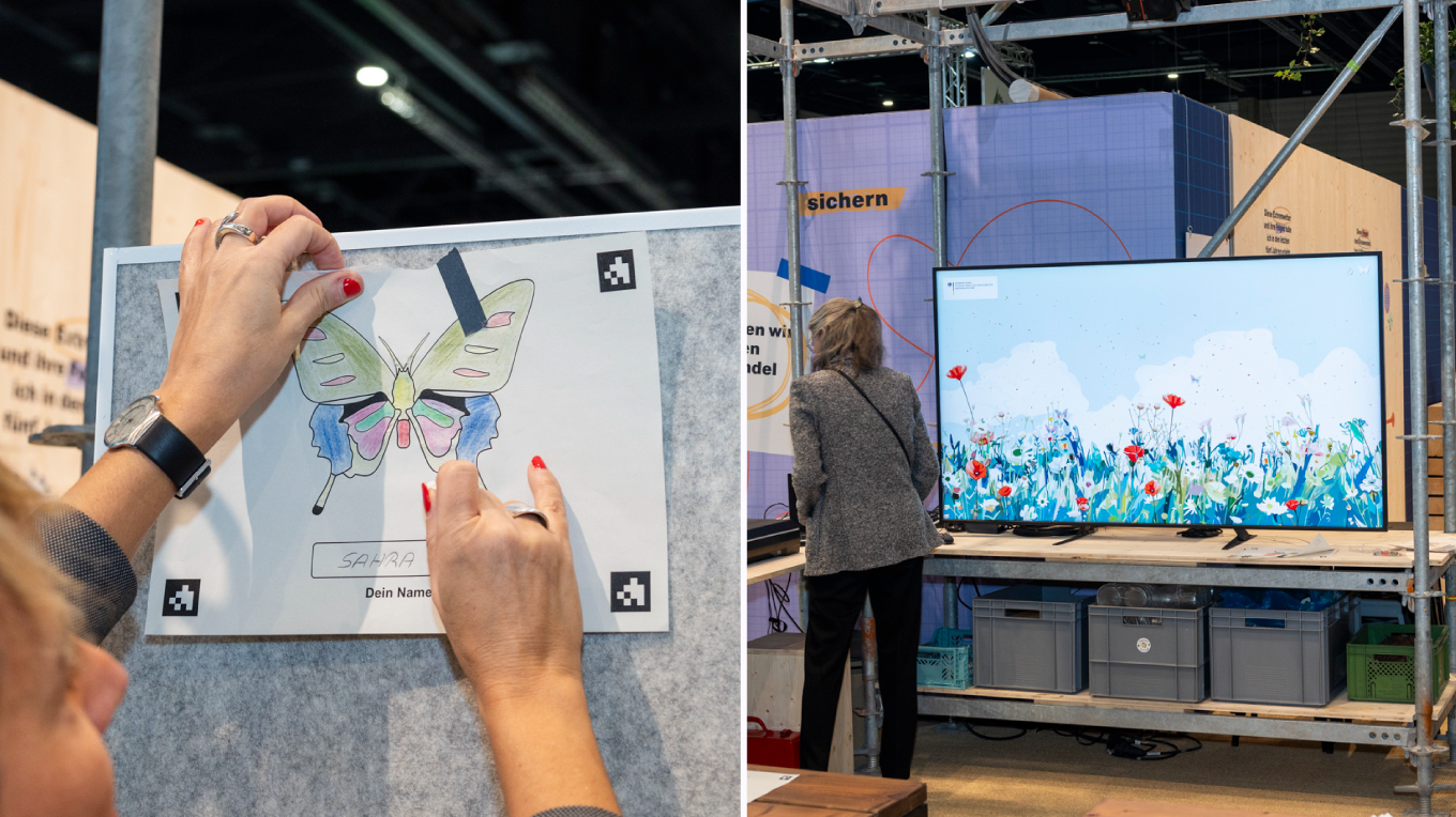 A person sticks a colored-in drawing of a butterfly on a wall. It was colored in by a visitor and animated on the screen of the Ministry of the Environment’s stand during the international Green Week (Grüne Woche) trade show.