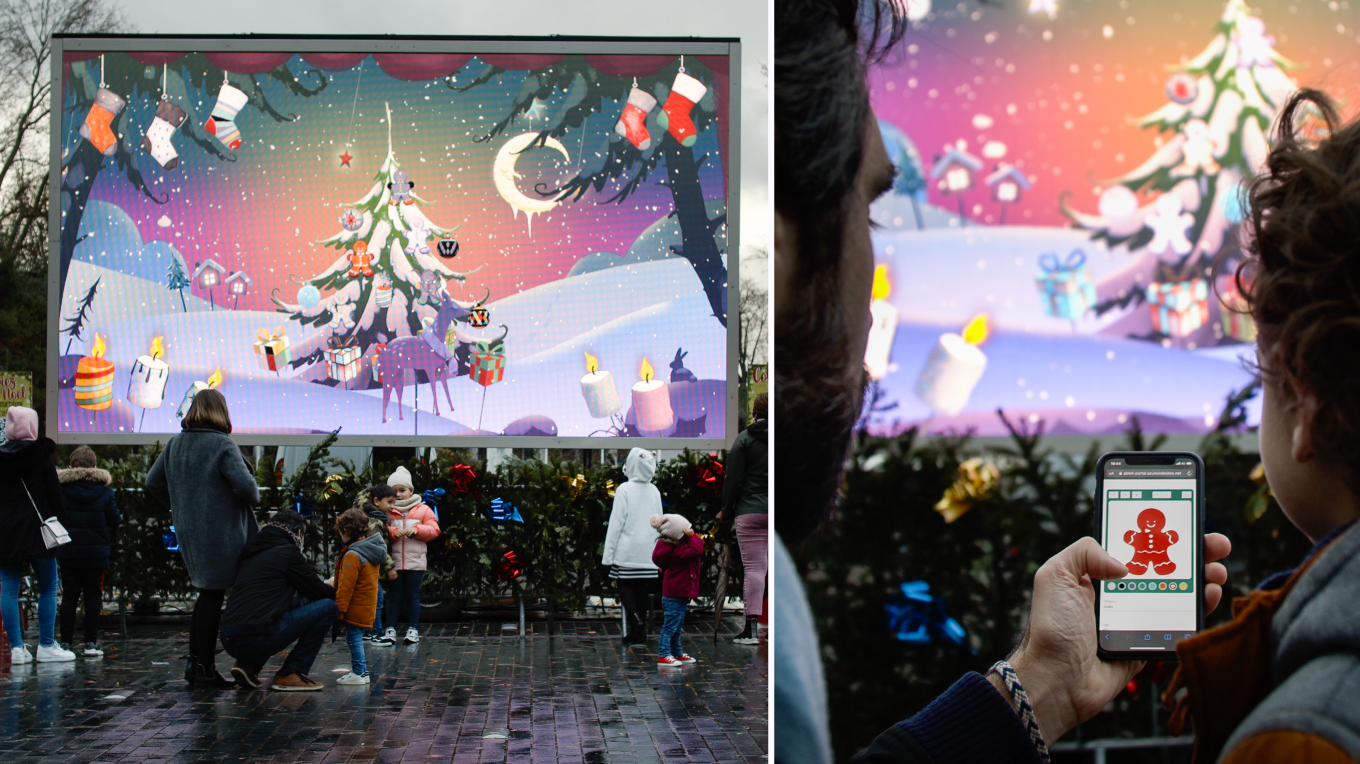 Un père et son enfant colorient un objet de Noël qu'ils voient s'afficher dans l'animation We Are Colors Christmas sur l'écran LED de la ville.