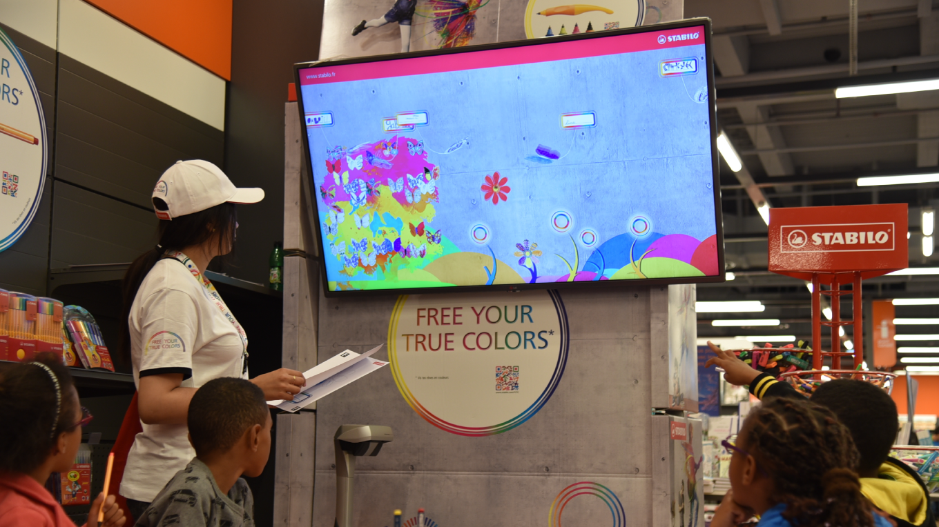Une animatrice du roadshow Free Your True Colors montre à un enfant son coloriage s’animer sur l’écran lors d’un atelier.